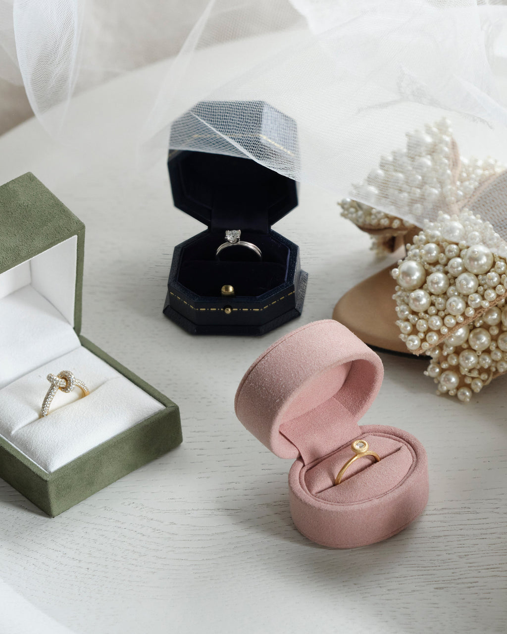 Jewelry box with rings and pearl-embellished shoes on a white surface