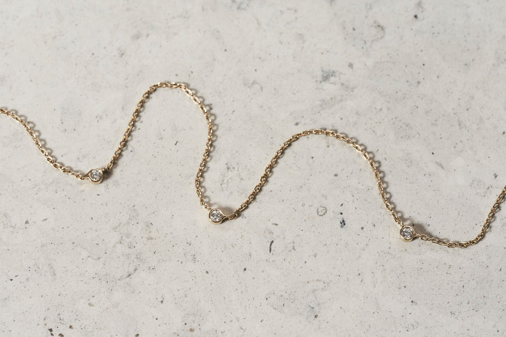 https://ik.imagekit.io/fzkghjurk1l/resize-external/https://storage.googleapis.com/shop_images/Akind/AKIND_StationDiamondNecklace_YG_Enviro.jpg?tr=w-2000,h-2000,c-at_max,f-jpg,bg-white