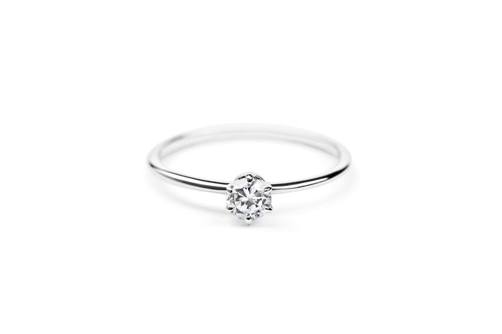 https://ik.imagekit.io/fzkghjurk1l/resize-external/https://storage.googleapis.com/shop_images/Akind/AKIND_SixProngDiamondRing0.3Ct_Laying_WG_Studio.png?tr=w-2000,h-2000,c-at_max,f-jpg,bg-white